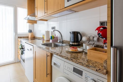 Modern kitchen with granite countertops, wooden cabinets, and stainless steel appliances in Haus Holiday Homes apartment