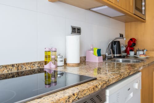 Modern kitchen with granite countertop, stainless steel appliances, and red kettle at Haus Holiday Homes apartment in San