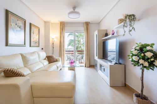 Bright modern apartment living room at Haus Holiday Homes in San Pedro del Pinatar with cream sofa, TV, plants, and balcony