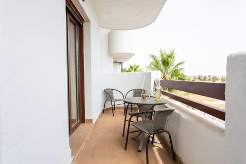 Sunny balcony at Haus Holiday Homes with seating, potted palms, and sea views in San Pedro del Pinatar