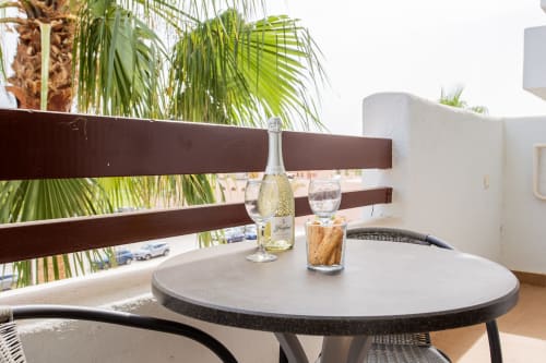 Modern apartment balcony at Haus Holiday Homes in San Pedro del Pinatar with round table, wine bottle, and palm tree views