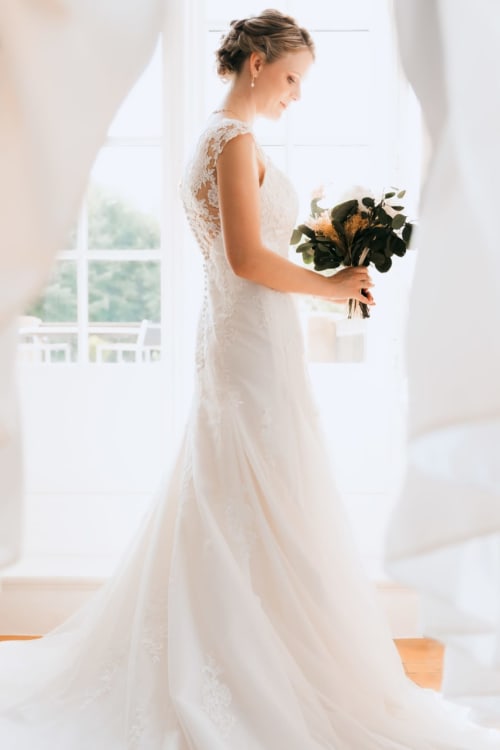 Bride in lace wedding dress with bouquet at Ô Château hotel, Hayange, France