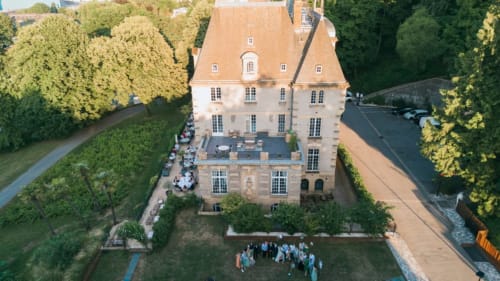 Aerial view of Ô Château hotel in Hayange, France with terracotta roofs, manicured gardens, and guests on the lawn