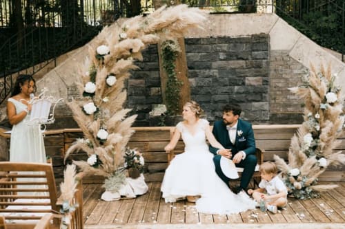 Wedding ceremony at Ô Château hotel in Hayange with bride, groom, and guests seated by pampas grass arch
