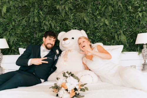 Joyful bride and groom with large teddy bear at Ô Château hotel in Hayange, France wedding celebration