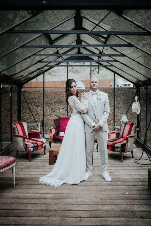 Bride and groom in greenhouse at Ô Château hotel, Hayange, with vintage red chairs and rural backdrop