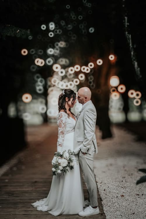 Bride and groom embrace under romantic lights at Ô Château hotel in Hayange
