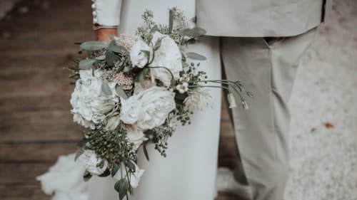 Bride holding white peony and sage wedding bouquet at Ô Château hotel in Hayange