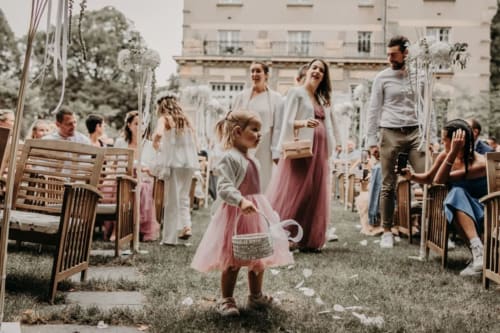 Outdoor wedding ceremony at Ô Château Hayange with guests seated and flower girl in pink dress