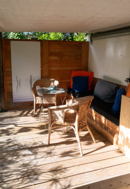 Terrazza ombreggiata al Lodge du Cap Ferret con sedie in vimini, tavolo rotondo e cuscini colorati