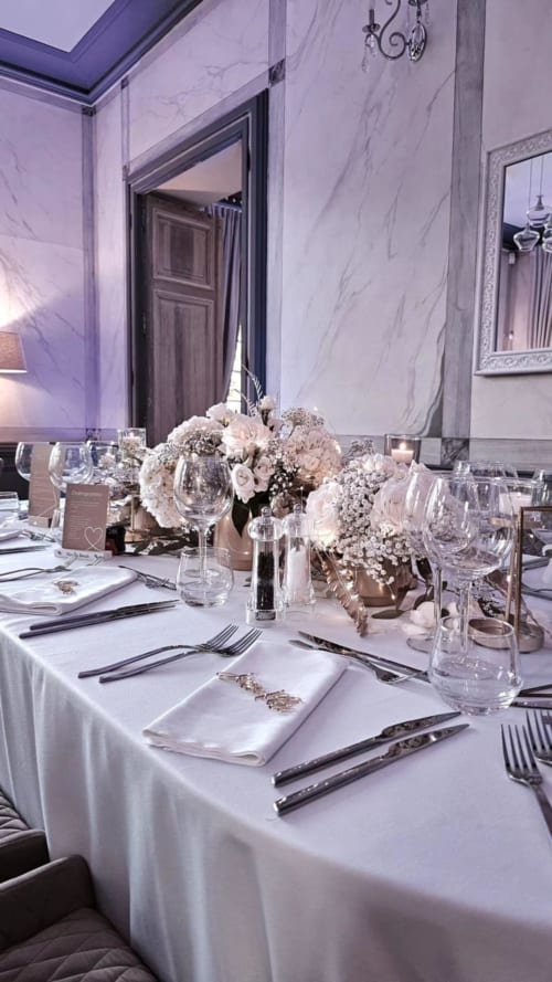 Elegant dining table at Ô Château hotel in Hayange with white linens, floral centerpieces, and formal place settings