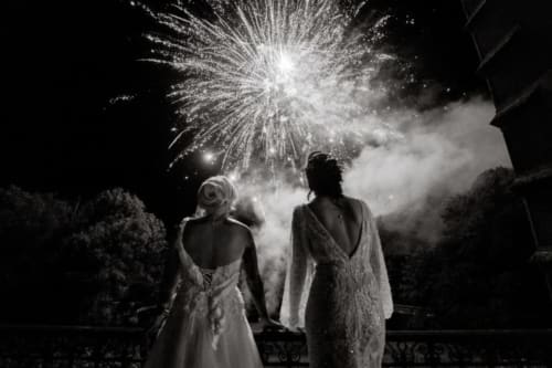 Two guests in wedding attire watching fireworks display at Ô Château hotel in Hayange, France at night