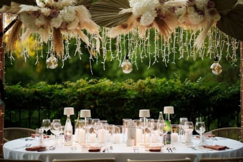 Elegant outdoor dining setup at Ô Château with floral arrangements, hanging lights, and place settings