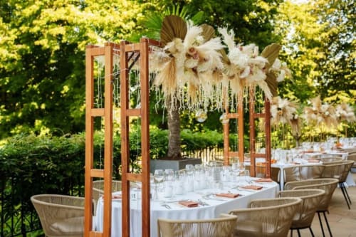 Elegant outdoor dining setup at Ô Château Hayange with wooden pavilion, draped florals, and linen-dressed tables.