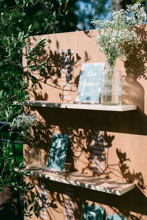 Elegant wedding seating chart display at Ô Château Hayange with white baby's breath flowers and guest name cards on wooden