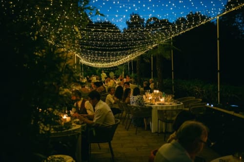 Evening garden dinner at Ô Château hotel in Hayange with string lights overhead and guests dining al fresco