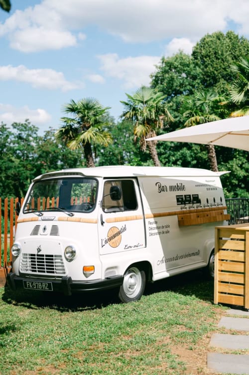 Vintage white food truck bar mobile at Ô Château hotel in Hayange with palm trees and cream umbrella