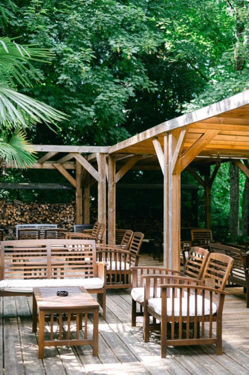 Wooden pergola terrace with lounge seating at Ô Château hotel in Hayange, surrounded by lush greenery