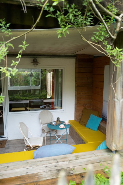 Accogliente sala da giardino al Lodge du Cap Ferret con sedute gialle, accenti turchesi e ingresso incorniciato dall'edera