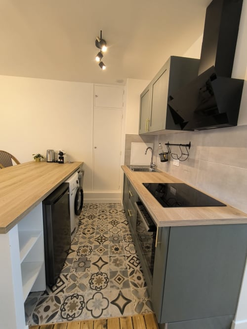 Cuisine couloir moderne à Enghien-les-Bains avec plan de travail bois, placards gris, plaque à induction et motifs