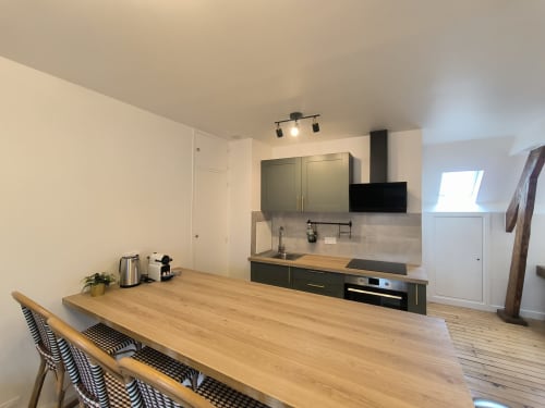 Cuisine et salle à manger contemporaines dans un appartement de Beauvais avec table en bois, meubles noirs et électroménagers en acier inoxydable