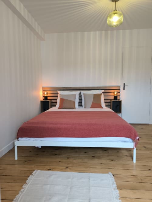 Chambre moderne dans un appartement d'Enghien-les-Bains avec literie rouge, lit à cadre blanc et éclairage ambiant chaleureux