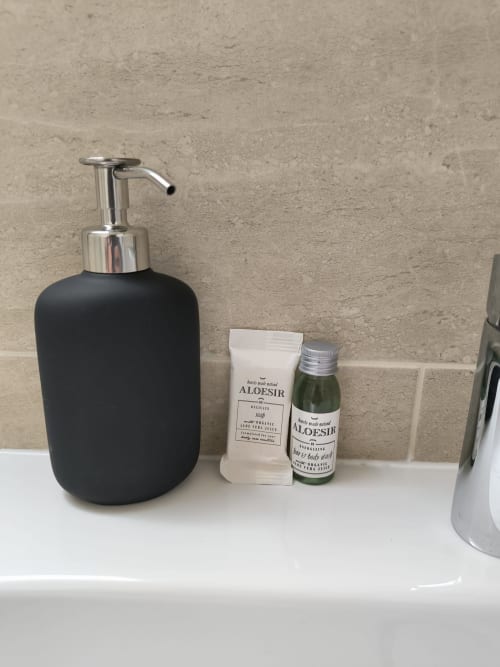 Distributeur de savon noir avec produits ALOESIR sur le comptoir de la salle de bains de l'appartement La Parisienne, Enghien-les-Bains