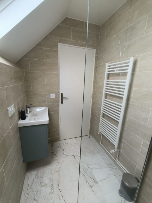 Salle de bains moderne dans un appartement d'Enghien-les-Bains avec carrelage, vasque, sèche-serviettes, toilettes et douche à l'italienne