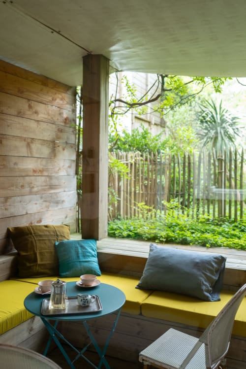 Terrazza privata con giardino al Lodge du Cap Ferret con seduta gialla incorporata, tavolo blu e vista sulla rigogliosa vegetazione