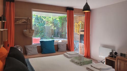 Camera moderna presso Le Lodge du Cap Ferret con seduta finestra, tende rosse, vista giardino e arredi contemporanei