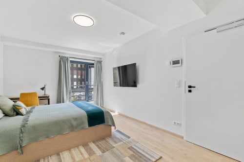Chambre moderne chez Mattbnb à Metz avec lit, télévision, balcon avec vue sur la ville et parquet