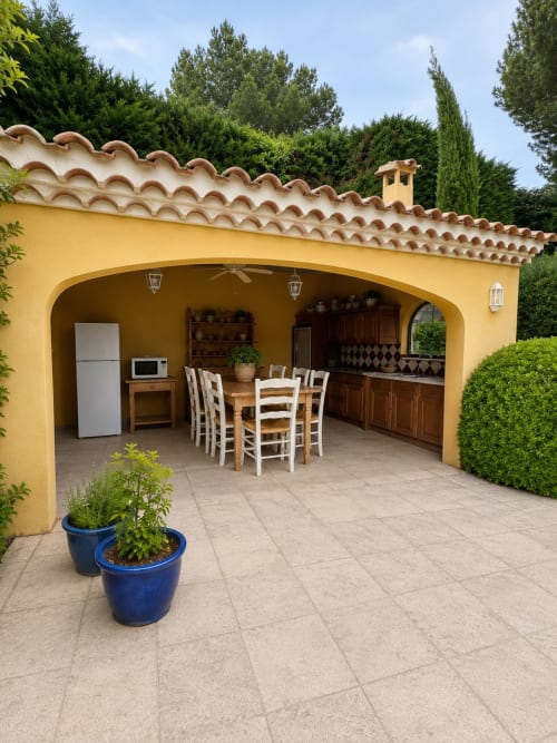 Villa jaune aux tuiles en terre cuite à la Conciergerie Maurin à Arles, avec patio couvert, table à manger et