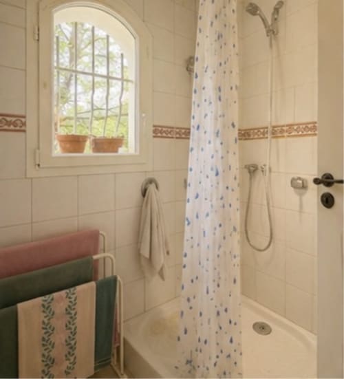 Salle de bains avec douche à la Conciergerie Maurin à Arles, murs carrelés et rideau bleu à motifs