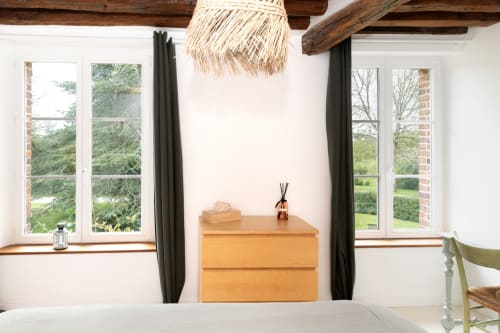Chambre lumineuse aux Lodges de la Ferme de la Chaise avec commode en bois, vue sur le jardin et poutres rustiques apparentes