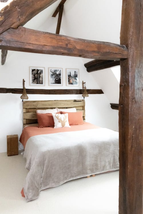 Chambre rustique du gîte Lodges de la Ferme de la Chaise avec poutres apparentes, lit en bois, literie corail