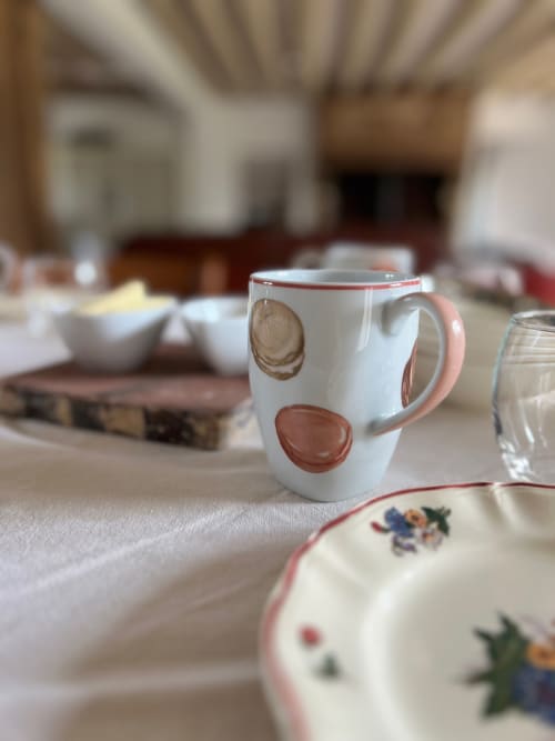 Tasse décorée avec assiette à fleurs sur la table du séjour du gîte Lodges de la Ferme de la Chaise