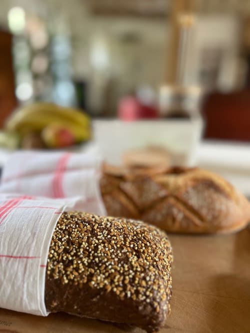 Pain aux graines de sésame enveloppé dans un tissu rayé aux Lodges de la Ferme de la Chaise, avec bananes et éléments de cuisine