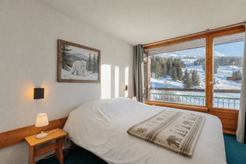Chambre avec vue sur les montagnes dans un appartement de ski à Bourg-Saint-Maurice, panorama enneigé des Alpes depuis le balcon, mobilier en bois et ambiance cosy