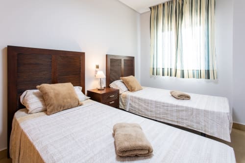 Twin beds with wooden headboards in bright bedroom at Haus Holiday Homes apartment, San Pedro del Pinatar