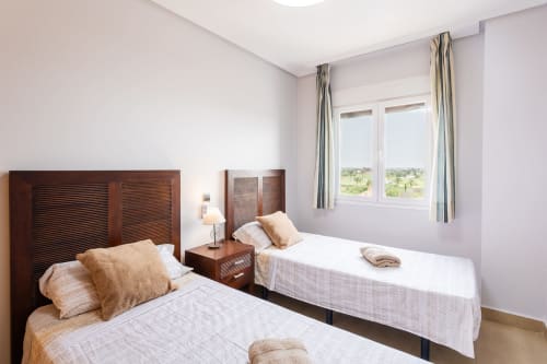 Twin bedroom with wooden headboards, white bedding, and sea view at Haus Holiday Homes apartment in San Pedro del Pinatar