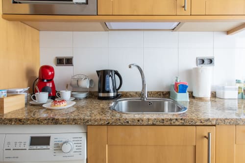 Modern kitchen countertop with sink, kettle, red coffee maker, and white tiles at Haus Holiday Homes apartment in San Pedro