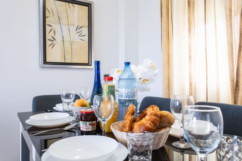Elegant dining table setup at Haus Holiday Homes with white place settings, fresh bread, water bottle, and white flowers