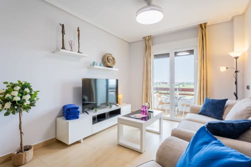 Modern living room in Apto. Plus Ultra apartment with blue accents, TV, comfortable seating, and balcony views in San Pedro