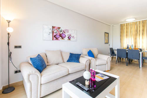 Modern living room in Apto. Plus Ultra apartment with cream sofa, blue pillows, and dining area in San Pedro del Pinatar