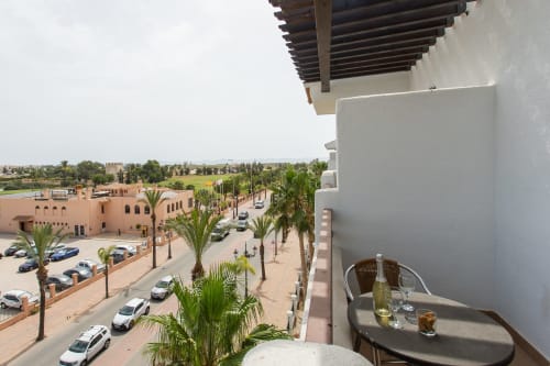 Balcony view of San Pedro del Pinatar with palm-lined plaza, terracotta buildings, and furnished outdoor seating at Haus