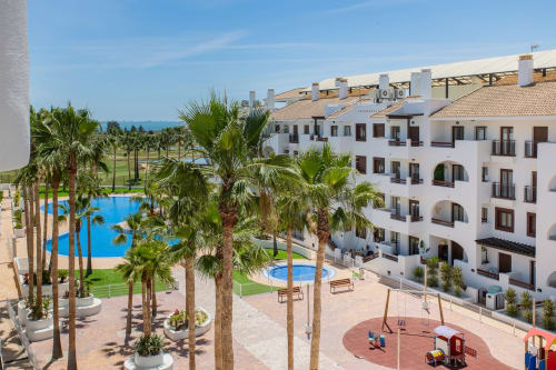 Haus Holiday Homes apartment complex in San Pedro del Pinatar with pools, palm trees, and children's playground
