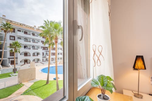 Bright apartment room with pool view overlooking palm trees and courtyard at Haus Holiday Homes in San Pedro del Pinatar