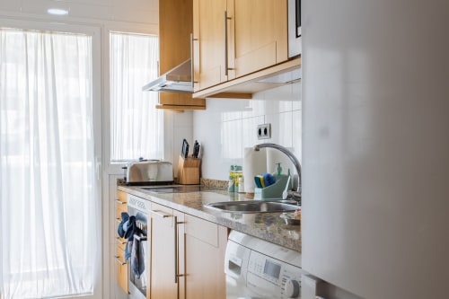 Modern kitchen in Alfa Living apartment at Haus Holiday Homes, San Pedro del Pinatar with wooden cabinets, granite