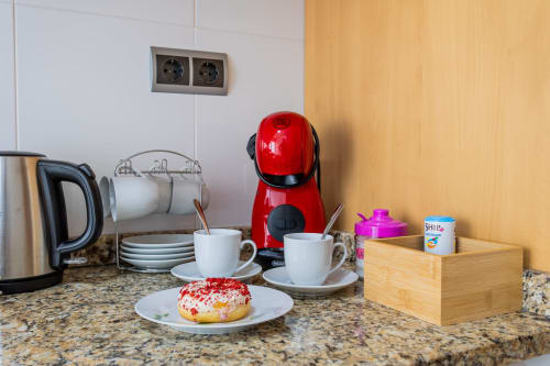 Kitchen counter at Haus Holiday Homes with red coffee maker, pastries, and white mugs in San Pedro del Pinatar apartment.