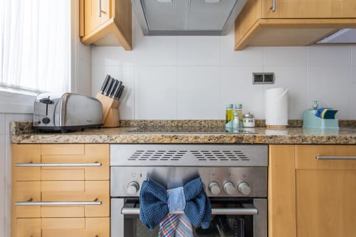 Modern kitchen with granite countertop, wooden cabinets, stainless steel oven, and white subway tile backsplash at Haus